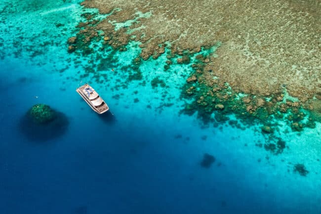 Silversonic dive boat anchored above large coral bommies on the Agincourt Ribbon Reefs, Great Barrier Reef.