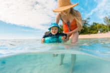 Mother and child swimming in shallow, calm turquoise water at Green Island.