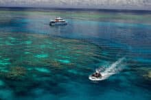 Poseidon dive tender transporting divers across vibrant coral bommies at the Agincourt Ribbon Reefs.