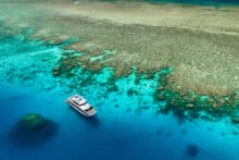 Silversonic dive and snorkel catamaran anchored over coral reef with snorkellers in turquoise water.