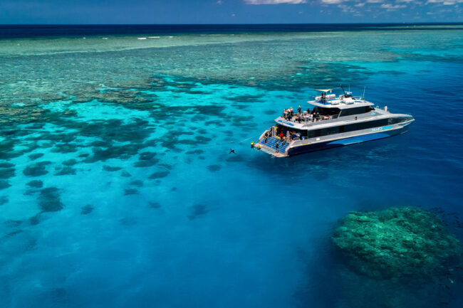 Silversonic dive and snorkel catamaran anchored over vibrant coral at Agincourt Reef near Port Douglas.