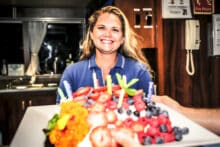 Smiling Reef Encounter crew member presenting a birthday cake on board
