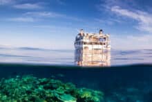 Over-under photo of Reef Encounter liveaboard above coral reef in clear blue water