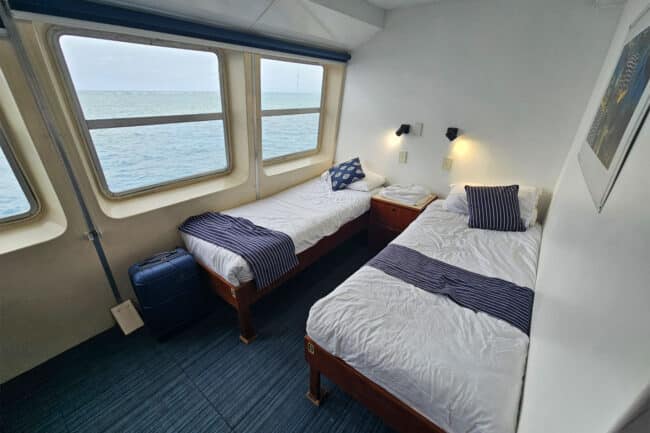 Twin ocean-view cabin on OceanQuest liveaboard with ensuite and large windows overlooking the Great Barrier Reef.