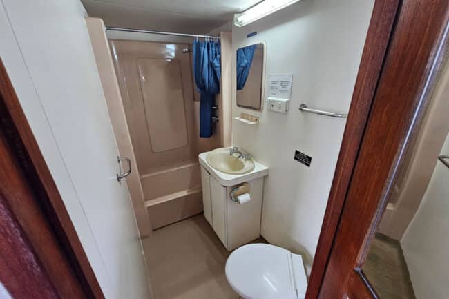 Private ensuite bathroom with shower, sink and toilet inside an OceanQuest Cairns liveaboard cabin.