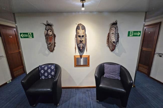 Lounge area on OceanQuest featuring traditional masks and guest seating between cabins.