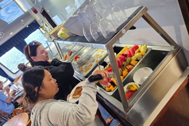 Guests enjoying breakfast buffet with fresh fruit and eggs aboard OceanQuest liveaboard.