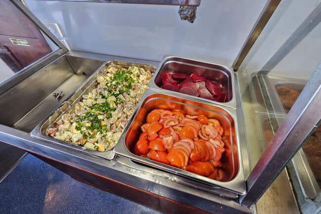 Fresh salads, tomatoes, beets & potato salad displayed on OceanQuest’s buffet line.