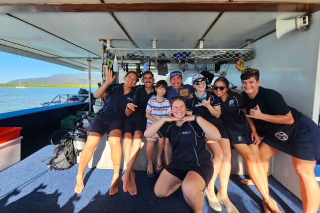 OceanQuest crew smiling with guests on the dive deck before departing Cairns Marina.