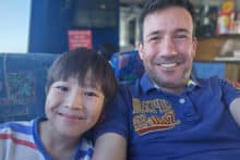 Father and son smiling on board the OceanQuest transfer vessel departing Cairns.