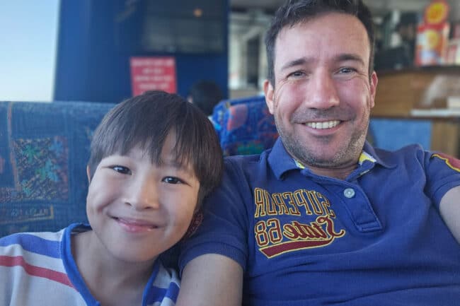 Father and son smiling on board the OceanQuest transfer vessel departing Cairns.