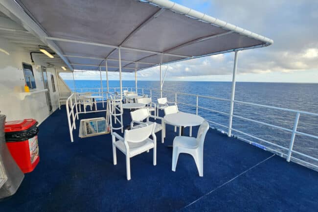 Top-deck bar and shaded seating area aboard OceanQuest overlooking the Coral Sea.