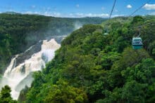 Skyrail gondola passing above Barron Falls in full flood surrounded by lush rainforest