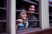 Father and daughter smiling as they look out the window of the Kuranda Scenic Railway train