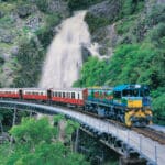 Kuranda Scenic Railway train crossing a bridge in front of Stoney Creek Falls near Cairns