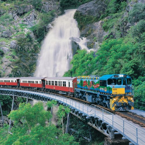 Kuranda Scenic Railway train crossing a bridge in front of Stoney Creek Falls near Cairns