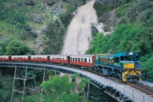 Kuranda Scenic Railway travelling across a bridge in front of Stoney Creek Falls near Cairns