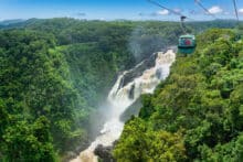 Skyrail gondola travelling above Barron Falls surrounded by dense tropical rainforest