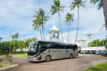 Tropic Wings tour coach pulling into a tropical resort for guest pickup