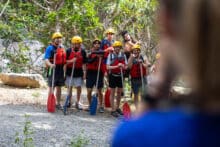Group of rafters wearing helmets and life jackets standing on a rainforest track before their Barron River white-water rafting tour in Cairns.