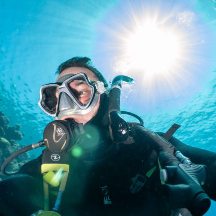 Scuba diver taking a selfie underwater in bright tropical sunlight on the Great Barrier Reef.