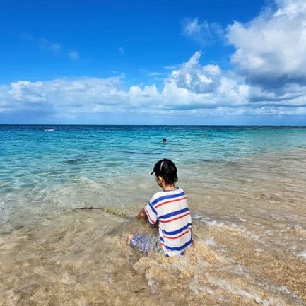 Child playing at the shoreline on a crystal clear beach at Green Island on the Great Barrier Reef